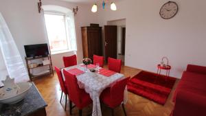 a living room with a table and red chairs at APARTMENT PALAZZO ŠARE in Vrbnik