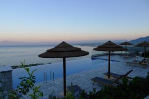 una piscina con sombrillas y sillas junto al agua en Petra Thea, en Kalamata