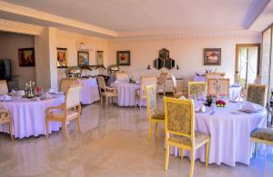 uma sala de jantar com mesas e cadeiras brancas em Hôtel Jnane Ain Asserdoune em Oulad Yaïch