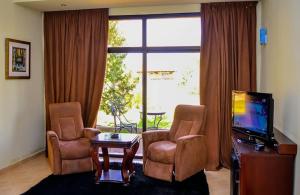 uma sala de estar com duas cadeiras e uma televisão em Hôtel Jnane Ain Asserdoune em Oulad Yaïch