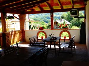 a patio with a table and chairs and a television at Pensiunea Casa Elena in Corbeni