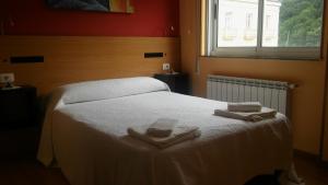 a bedroom with a bed with two towels on it at Hostal-Meson Vilasante in Treacastela