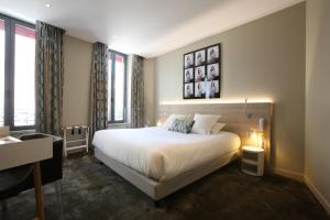 sypialnia z dużym białym łóżkiem i oknami w obiekcie Hotel De France w mieście Valence