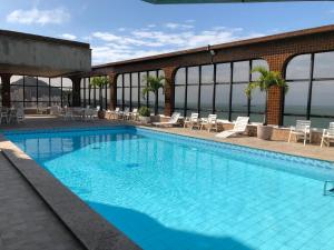 a large swimming pool with chairs and tables at Flat Pasargada 1013 in Vila Velha