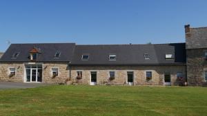 a large stone building with a grass field in front at La ferme Guibel in Plouzélambre