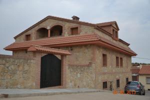 un edificio de ladrillo con una puerta y un garaje en Apartamentos Rurales Natura, en Torrejón el Rubio