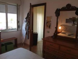 Schlafzimmer mit einem Bett, einer Kommode und einem Spiegel in der Unterkunft Appartamento Foglie in Bovalino Marina