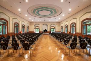 un hall vide avec des chaises et un piano en arrière-plan dans l'établissement TH Borca di Cadore - Park Hotel Des Dolomites, à Borca di Cadore