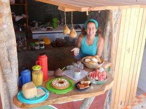 a woman standing in a booth with a table of food at Raízes Eco Hostel in Barra Grande