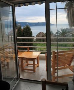 een balkon met een houten tafel en uitzicht op de oceaan bij Koi Seaview apartment in Herceg-Novi