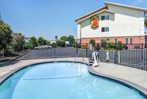 a swimming pool in front of a building with a fence at Super 8 by Wyndham Sacramento/Florin Rd in Sacramento