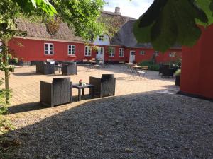 BrammingにあるAlsbrogaardの赤い建物の前にテーブルと椅子が置かれた中庭