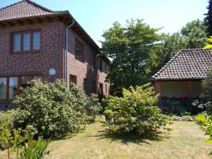 a brick house with bushes in the yard at Lindenzimmer Stöcken in Oetzen