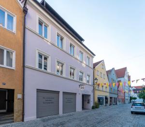 a white building on a street with flags at Old Town Apartments in Kaufbeuren