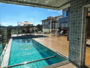 a swimming pool with a view of a house at Suítes de Luxo Paraíso de Minas Escarpas in Capitólio
