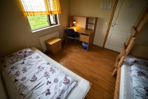a bedroom with a bed and a desk and a window at Berg Hostel in Húsavík