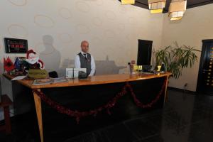 a man standing behind a desk with a santa claus behind it at Hotel Class in Vorë