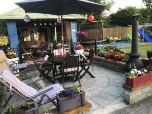 Barrow View Accommodation في Mountmellick: فناء مع كراسي وطاولة مع مظلة