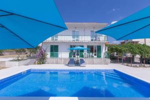 a swimming pool with blue umbrellas in front of a house at Holiday apartment in Vodice