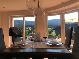 Schwarzwald Lodge Oppenau في أوبناو: طاولة غرفة الطعام مع كؤوس النبيذ وإطلالة