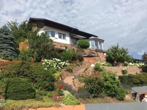 Schwarzwald Lodge Oppenau في أوبناو: منزل على تلة فيها نباتات وزهور