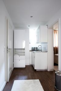 una cocina blanca con armarios blancos y fregadero en Ellena`s FEWO am Uke, en Hamburgo