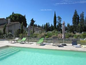 un grupo de sillas y sombrillas junto a una piscina en Gite Les Courlis, en Saint-Étienne-du-Grès