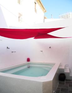 ラ・ヌシアにあるCasa Paradiseの白い部屋のバスタブ(赤いカーテン付)