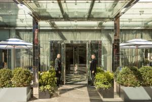 deux hommes marchant dans un bâtiment en verre avec des parapluies dans l'établissement Hotel Hayden New York, à New York