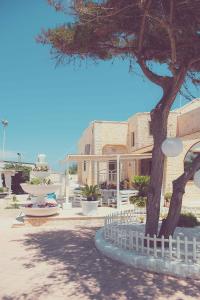 ein Gebäude mit einem Baum und einem weißen Zaun in der Unterkunft Hotel San Giovanni in Polignano a Mare