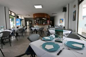 un restaurante con mesas y sillas blancas y una mesa con platos en Hotel Candano, en Isla