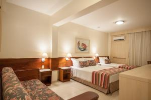 a hotel room with two beds and a couch at Saint Peter Hotel São Jose do Rio Preto in Sao Jose do Rio Preto
