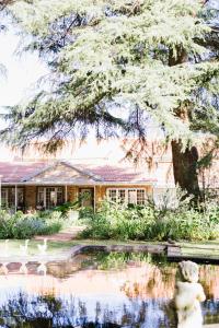 dom ze stawem przed nim w obiekcie A Country Garden Guest House w mieście Potchefstroom