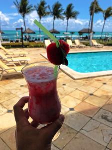 Una mano sosteniendo una bebida con una cereza encima en Flat Apart Hotel Marinas Tamandaré, en Tamandaré