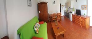 salon z zieloną kanapą i kuchnią w obiekcie Apartamentos Casa María w mieście Agulo
