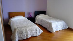 una camera con 2 letti con coperte bianche su un pavimento in legno di Sea View House a Ribeira Brava
