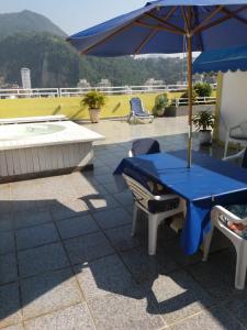 a blue table and chairs with an umbrella and a pool at Penthouse Botafogo Rio de Janeiro in Rio de Janeiro