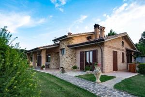 una casa de ladrillo con un jardín delante de ella en B&B Madonna Carradori, en Offagna