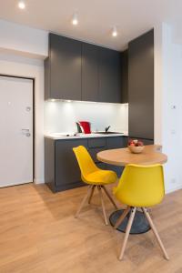 a kitchen with a table and two yellow chairs at Arbans Elegant apartment in the city center in Bucharest