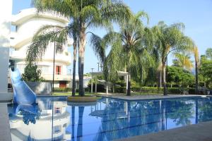 een zwembad met palmbomen en een waterglijbaan bij The Lorian Club in Cocoyoc
