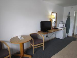 Habitación con escritorio, TV y mesa. en Cassville Budget Inn, en Cassville