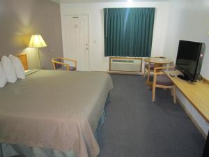 a hotel room with a bed and a desk with a television at Cassville Budget Inn in Cassville