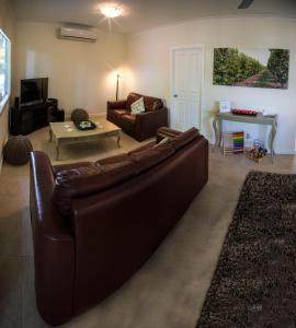 ein Wohnzimmer mit einem braunen Sofa und einem Tisch in der Unterkunft Farview Guest Accommodation in Pickering Brook