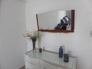 a mirror on a wall with a vase on a dresser at Francia Apartment in Santa Fe