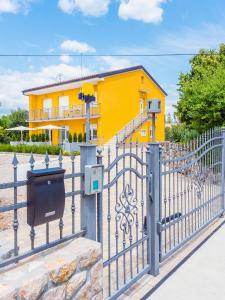 a fence in front of a yellow house at Appartments Adriatic in Omišalj