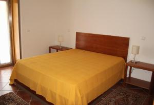 a bedroom with a yellow bed with two tables at 'Casa do Afonso' in Esposende