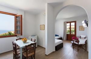 a living room with a table and a room with a bed and a window at Venetia Apartments in Monemvasia
