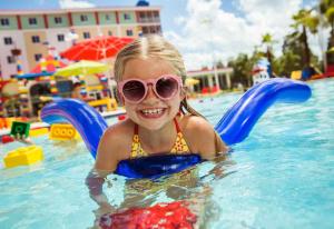 a little girl in a swimming pool wearing sunglasses at LEGOLAND California Hotel and Castle Hotel in Carlsbad