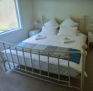 Una cama con sábanas blancas y almohadas en un dormitorio en Farview Guest Accommodation, en Pickering Brook