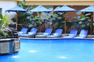 einen Pool mit blauen Stühlen und Sonnenschirmen in der Unterkunft SenS Hotel and Spa in Ubud